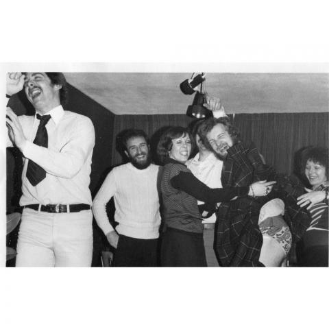 Black and white image of folk at a home party  in the 1970s