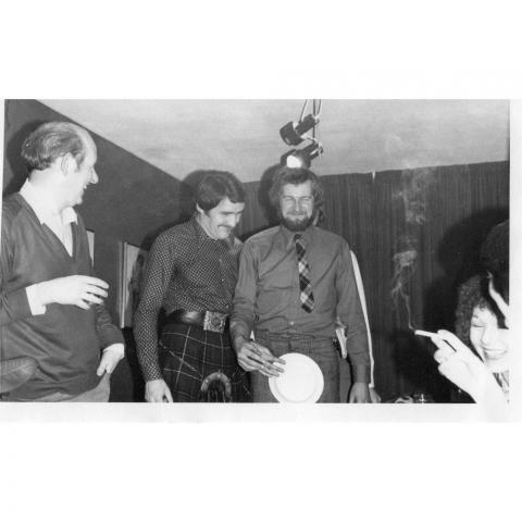 Black and white image, men in kilts at party 